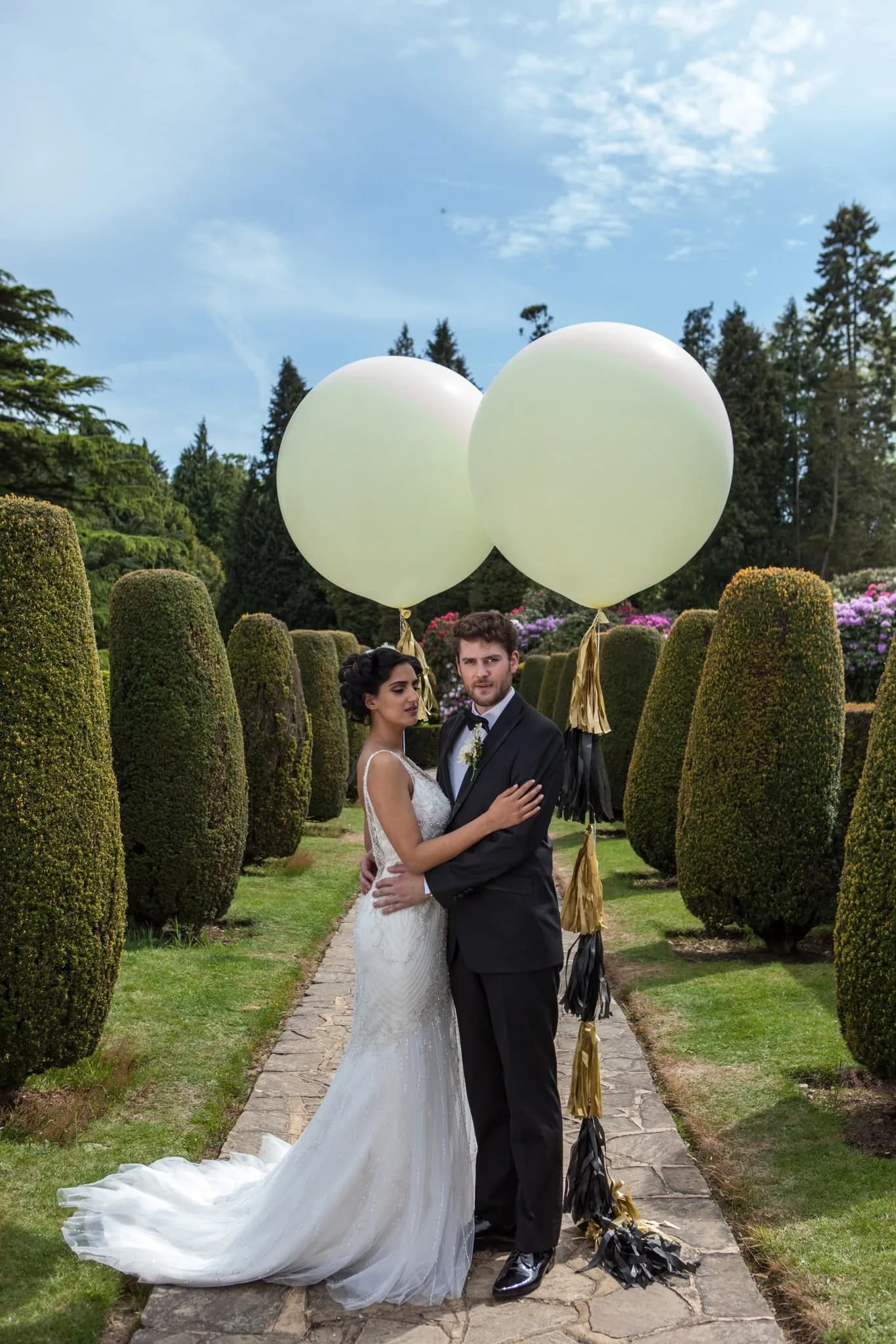 Couple with oversized balloons in a topiary garden