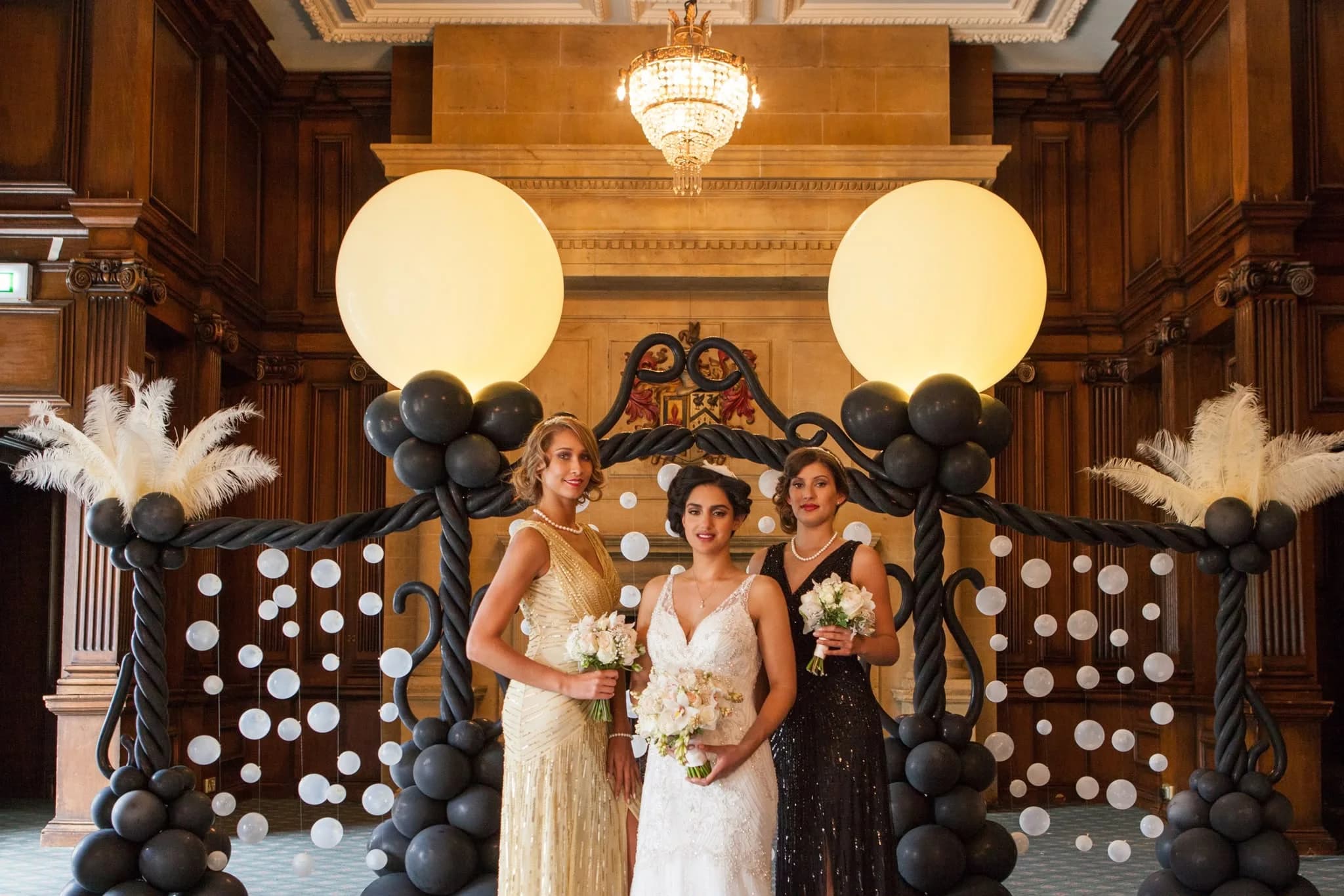 Bride and bridesmaids beneath a feathered balloon arch