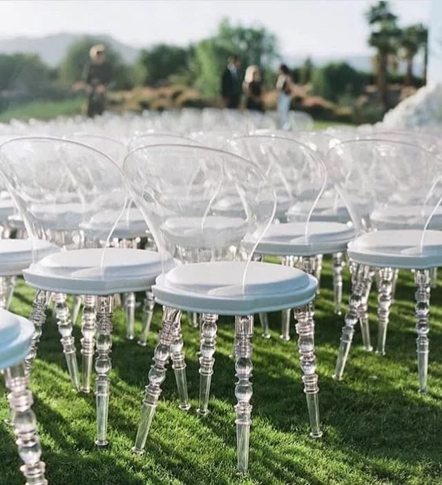 Rows of clear chairs set out for an outdoor ceremony
