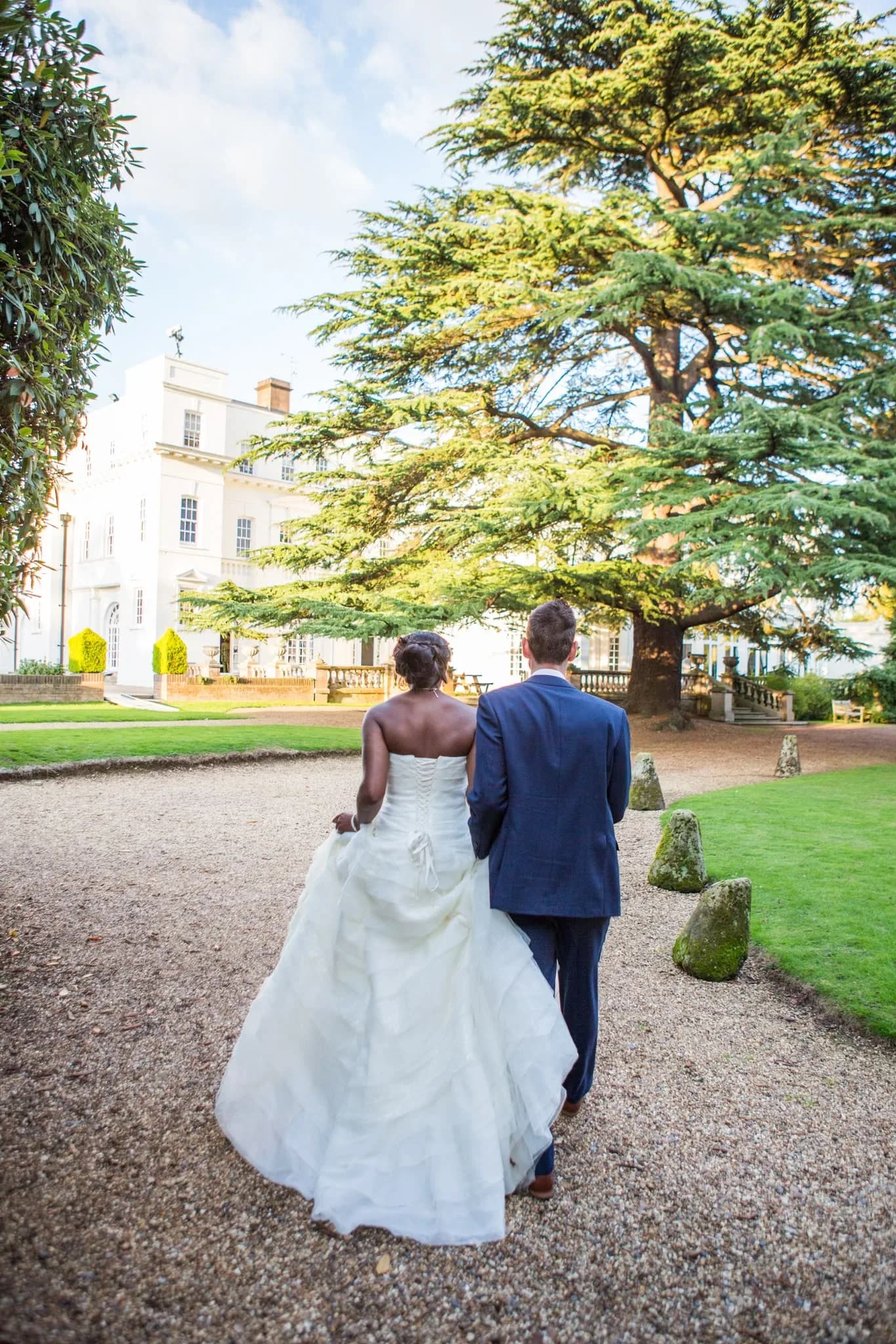 Bride and groom walking through manor house gardens